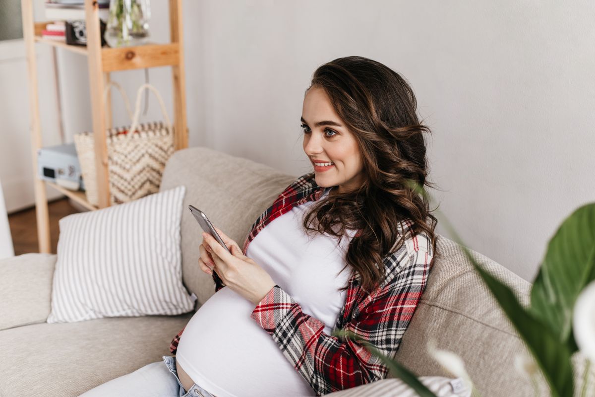 Gestante usando o celular em casa